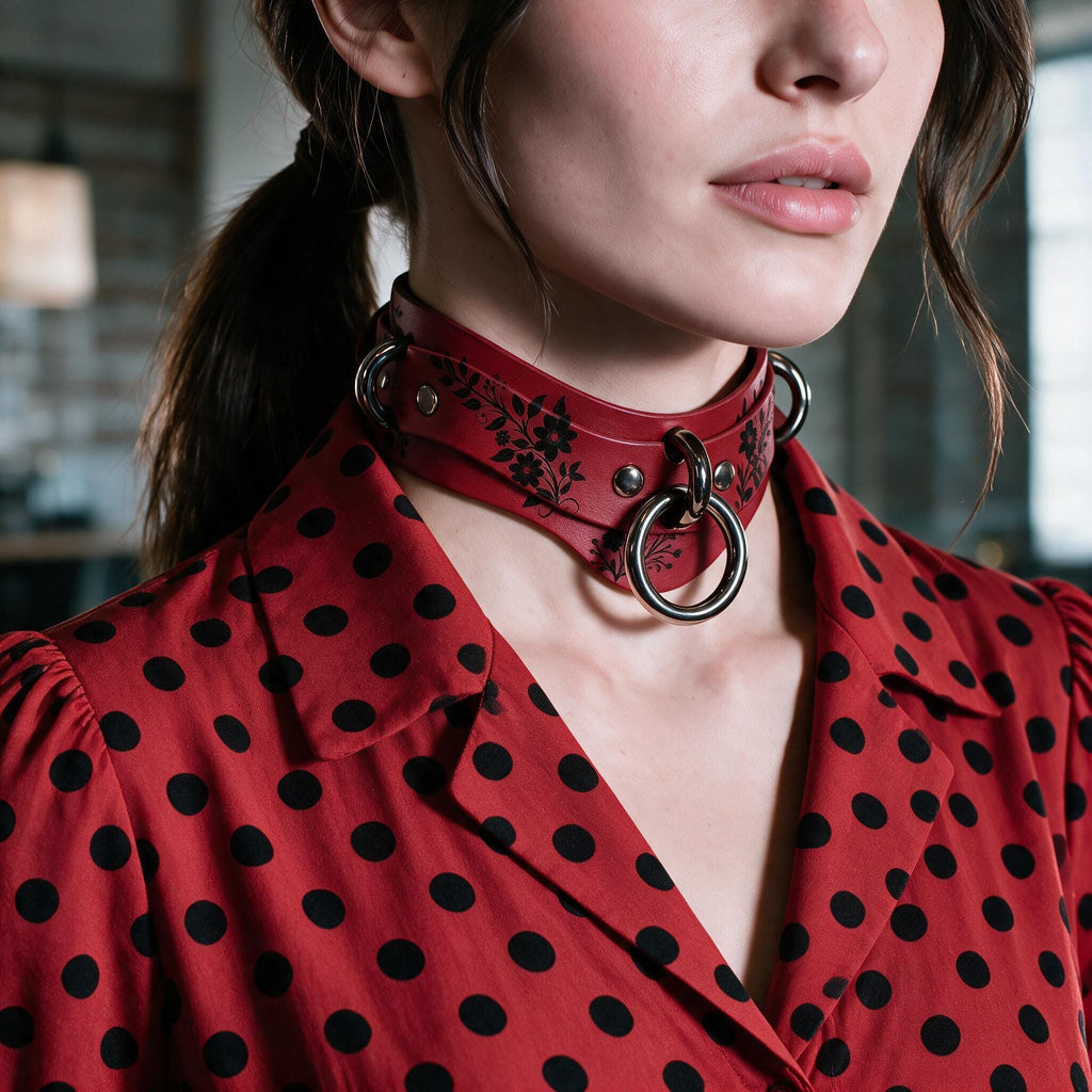 A close-up of a woman wearing a red dress with black polka dots and a choker necklace with metal rings.