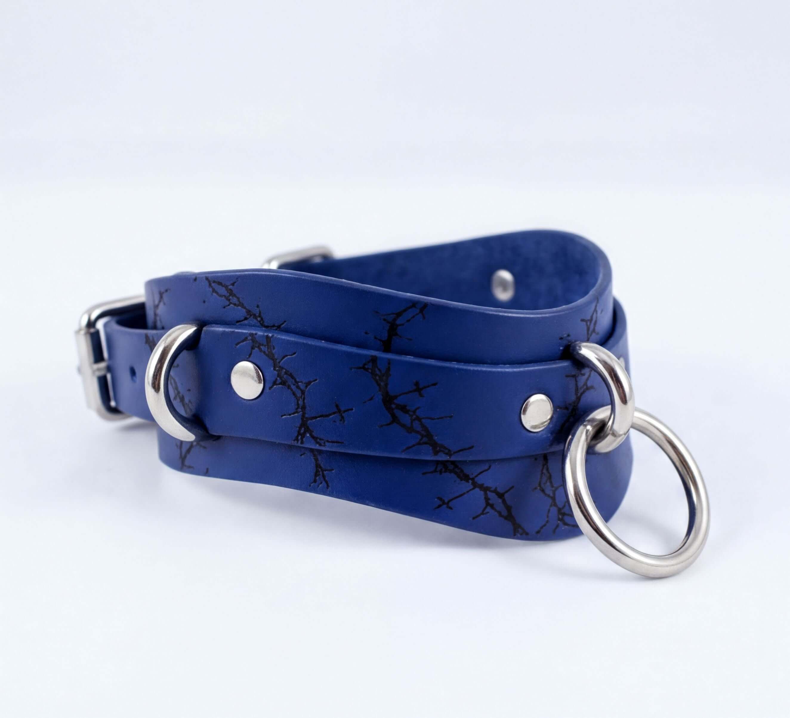 A blue leather choker necklace with a silver metal ring and two metal rings on the ends.