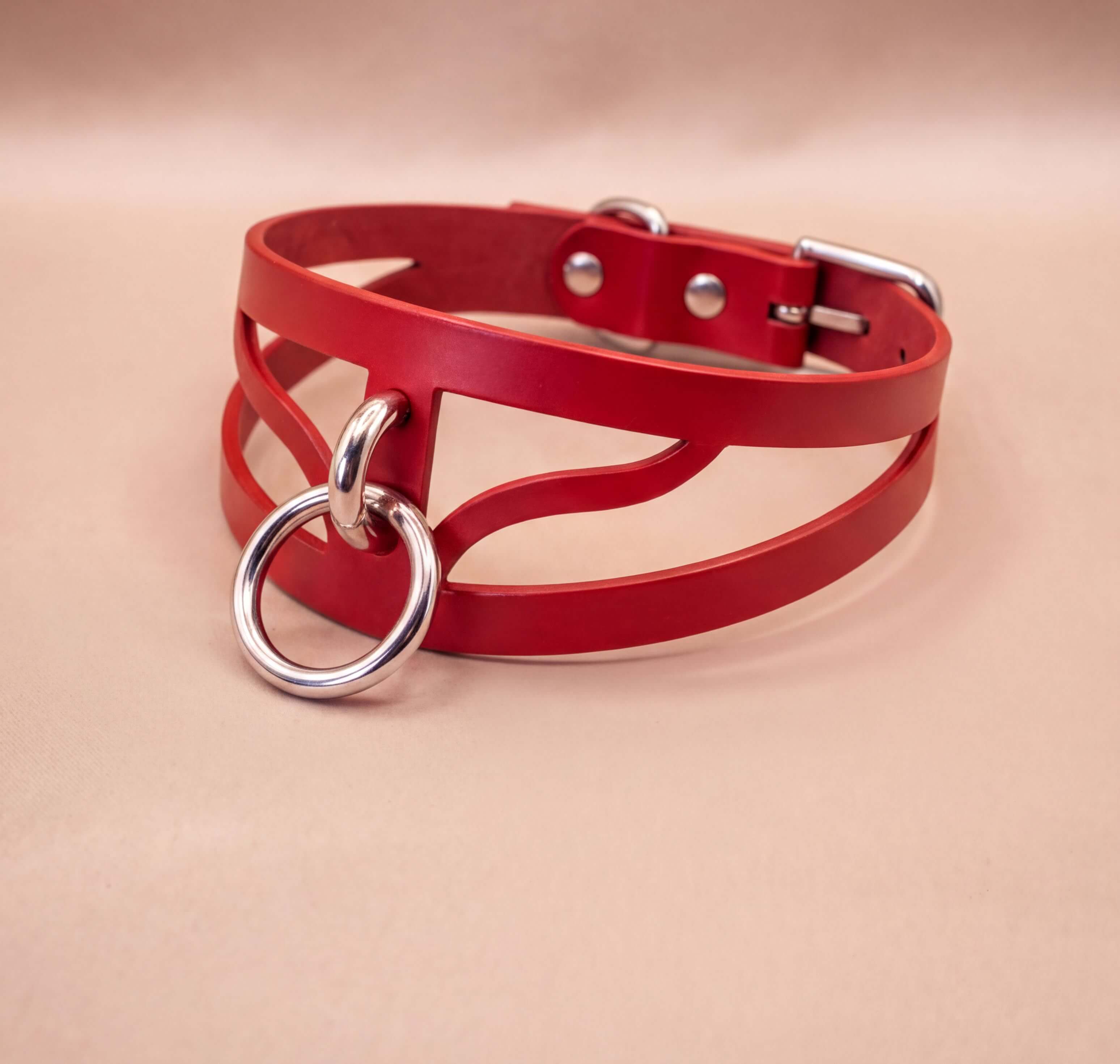 A red leather choker necklace with a metal ring and buckle.
