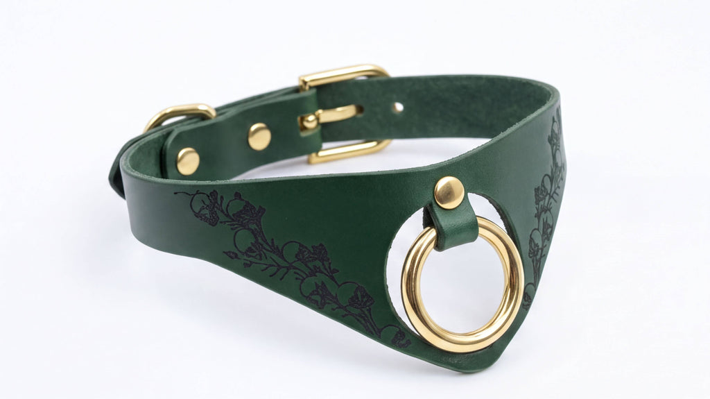 A green leather choker necklace with a gold-colored metal ring and a decorative floral pattern on the front.