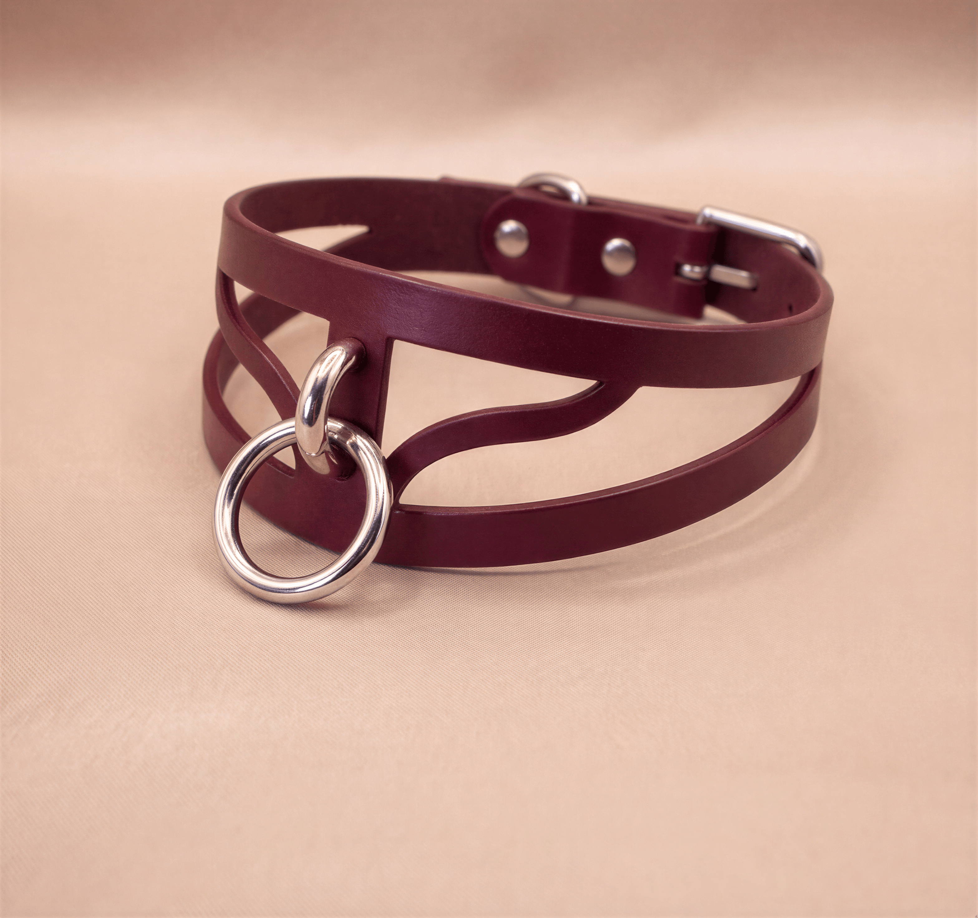 A burgundy leather choker necklace with a metal ring and buckle.