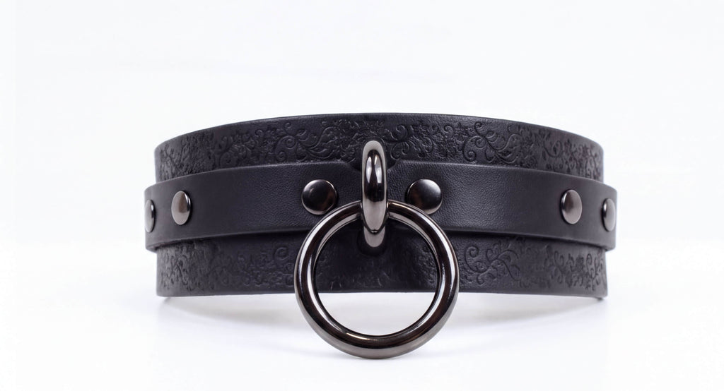 A black leather choker necklace with a metal ring and metal studs on the front.