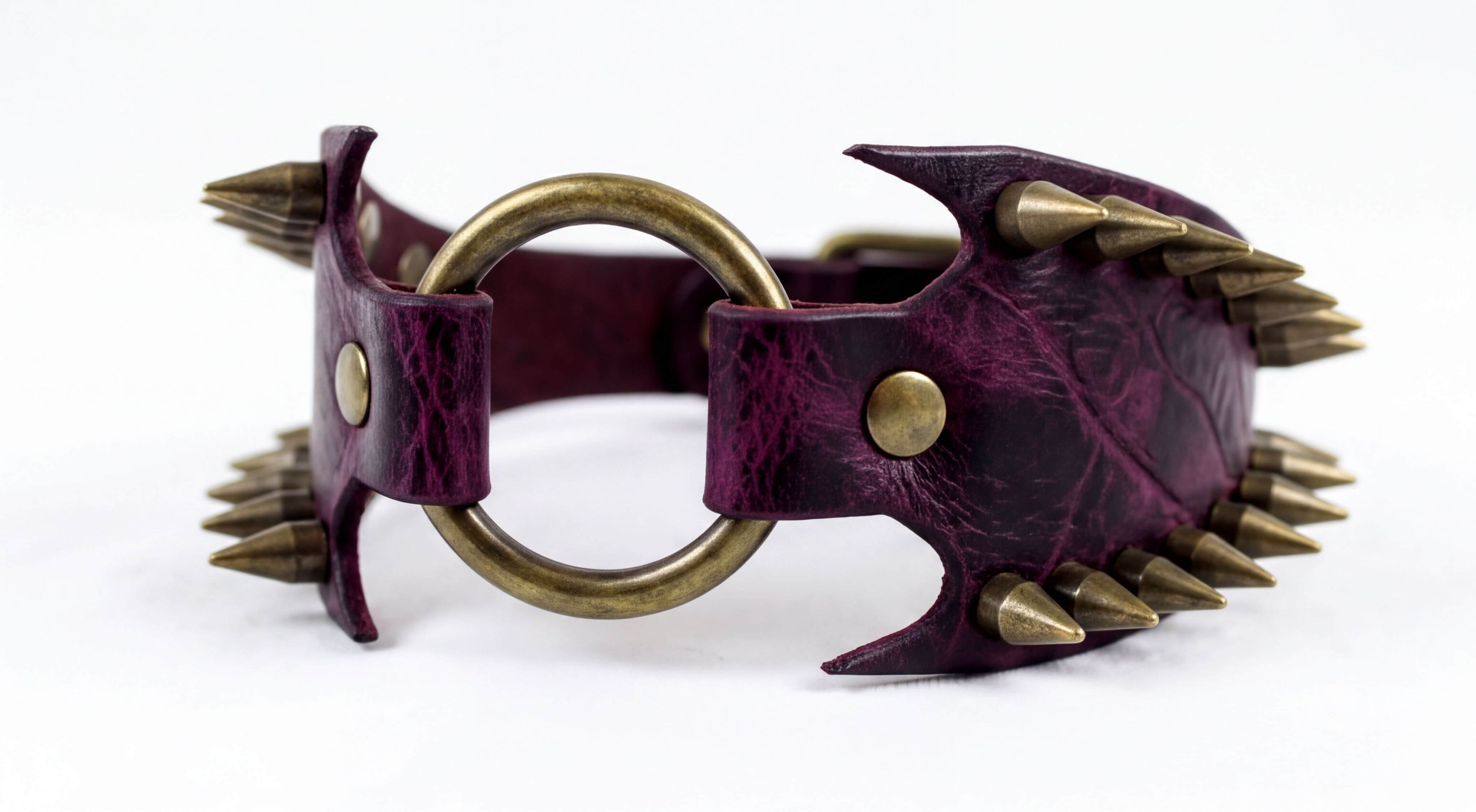 A purple leather choker necklace with a circular metal ring and spikes protruding from it.