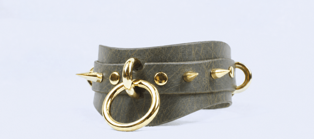 A leather choker necklace with gold studs and a gold ring.