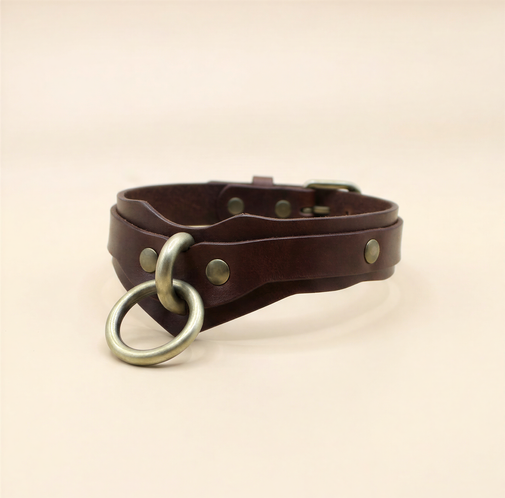 A brown leather choker collar with metal rings and buckles.
