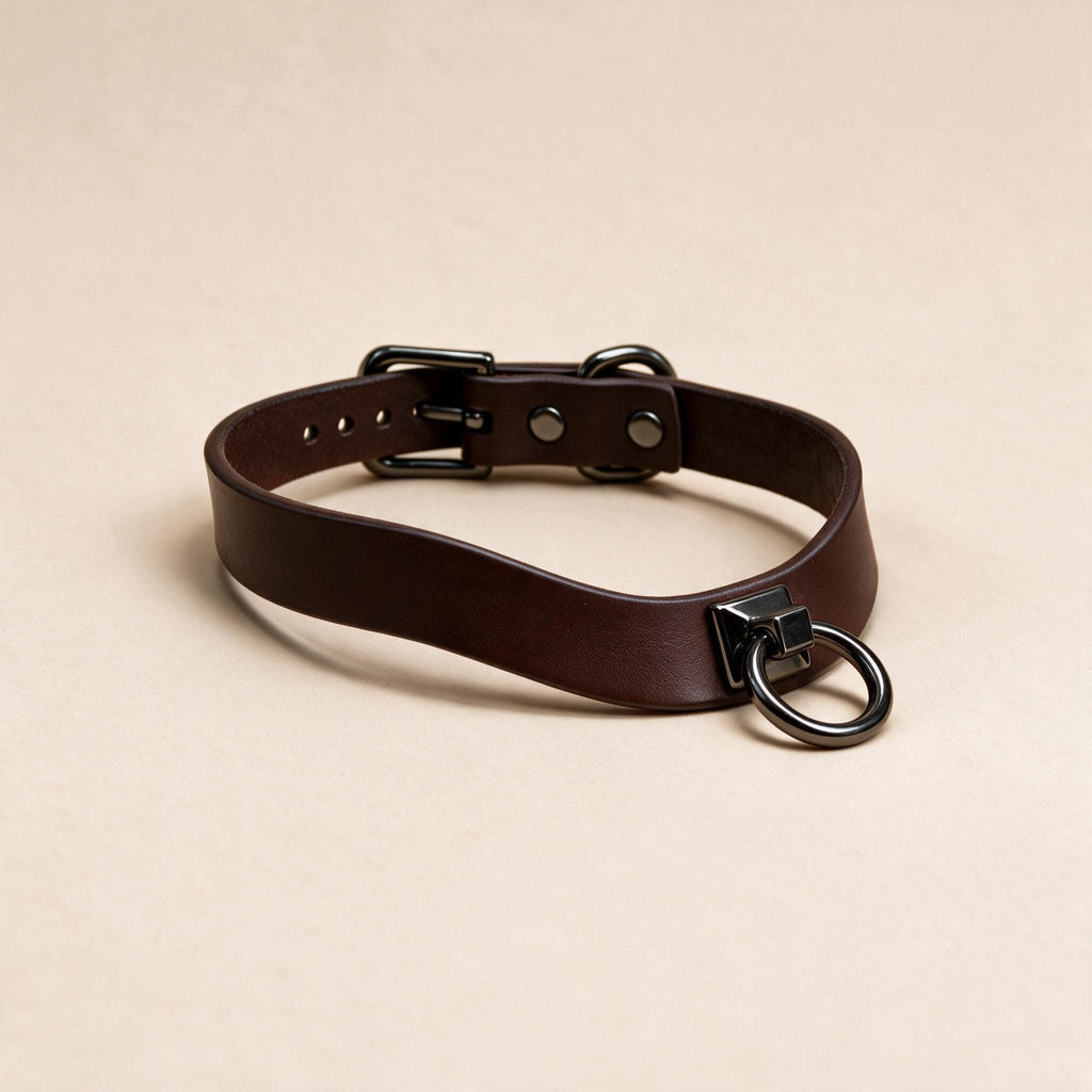A brown leather choker collar with a metal ring and buckle.