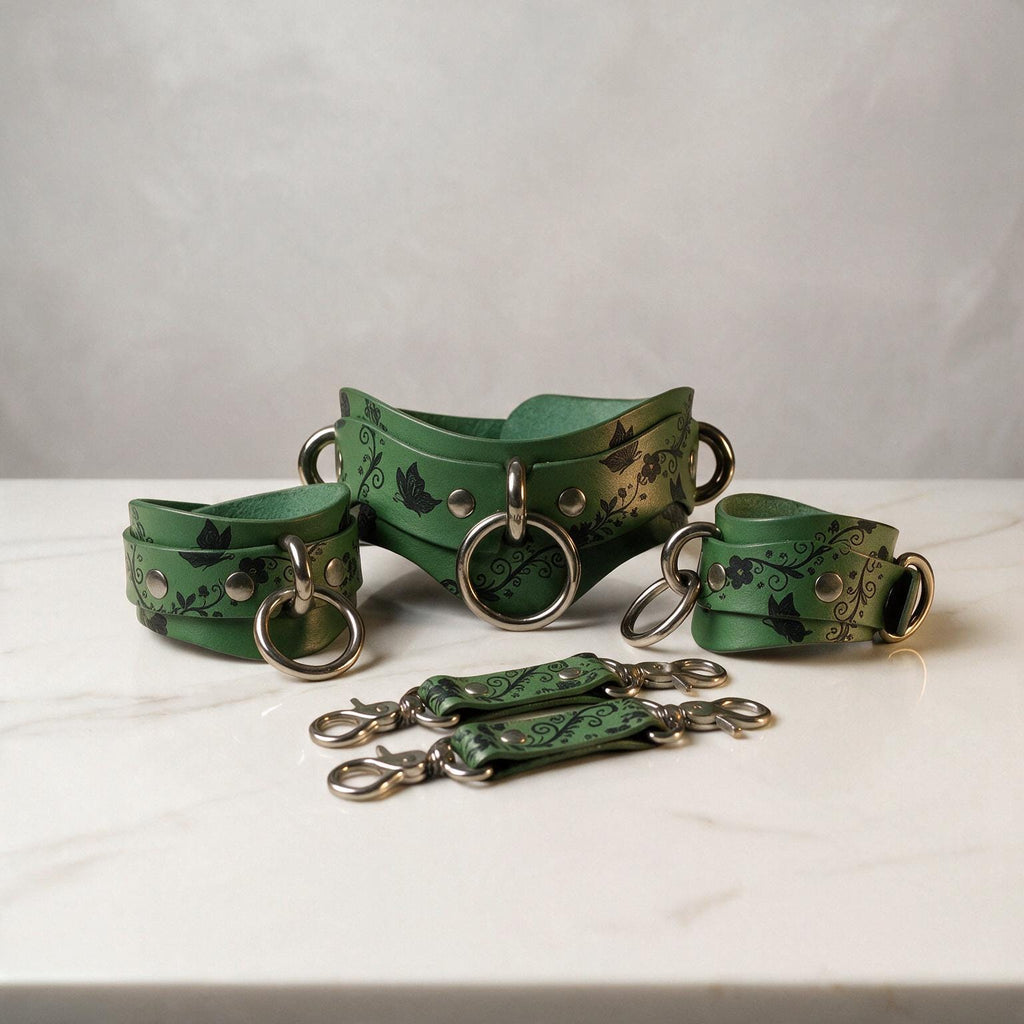 A set of green leather straps with metal rings and buckles, arranged on a white marble surface.
