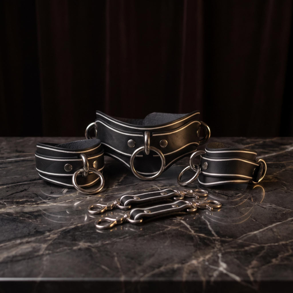 A set of black leather straps with metal rings and buckles, arranged on a marble surface.