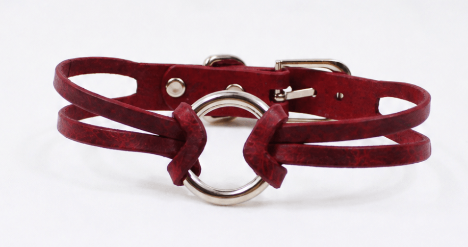 A red leather choker necklace with a metal ring and buckle.