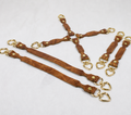 a collection of brown leather straps with gold hardware, including heart-shaped buckles, arranged on a white background.