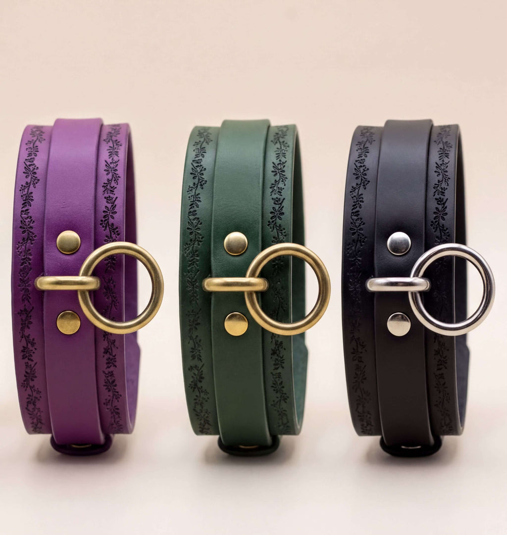 Three leather bracelets with metal rings and decorative patterns on them, arranged in a row.