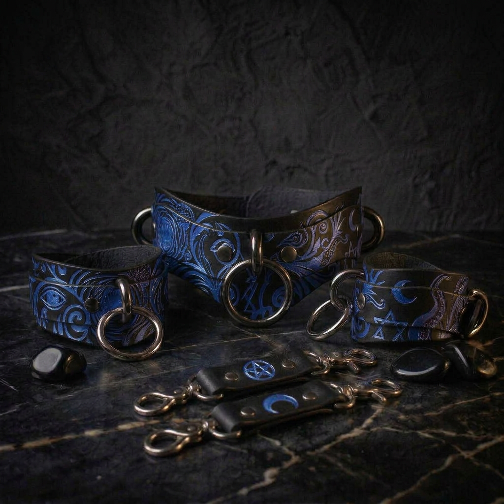 A collection of dark-colored leather accessories, including collars, cuffs, and straps, with intricate blue and black designs. The accessories are arranged on a dark surface, creating a striking contrast.