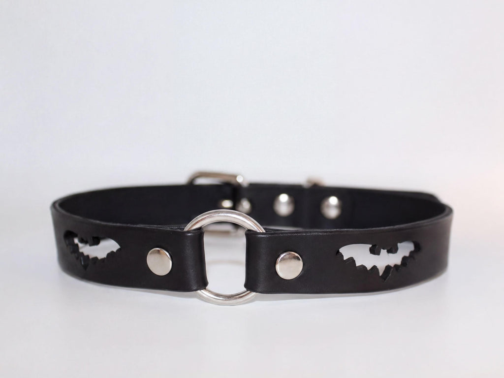 A black leather collar with a silver buckle and bat-shaped cutouts.