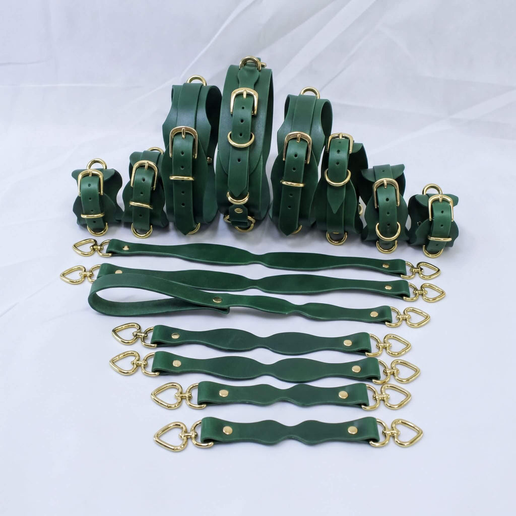 A collection of green leather straps with gold buckles, arranged in various sizes and shapes, likely for use in clothing or accessories.
