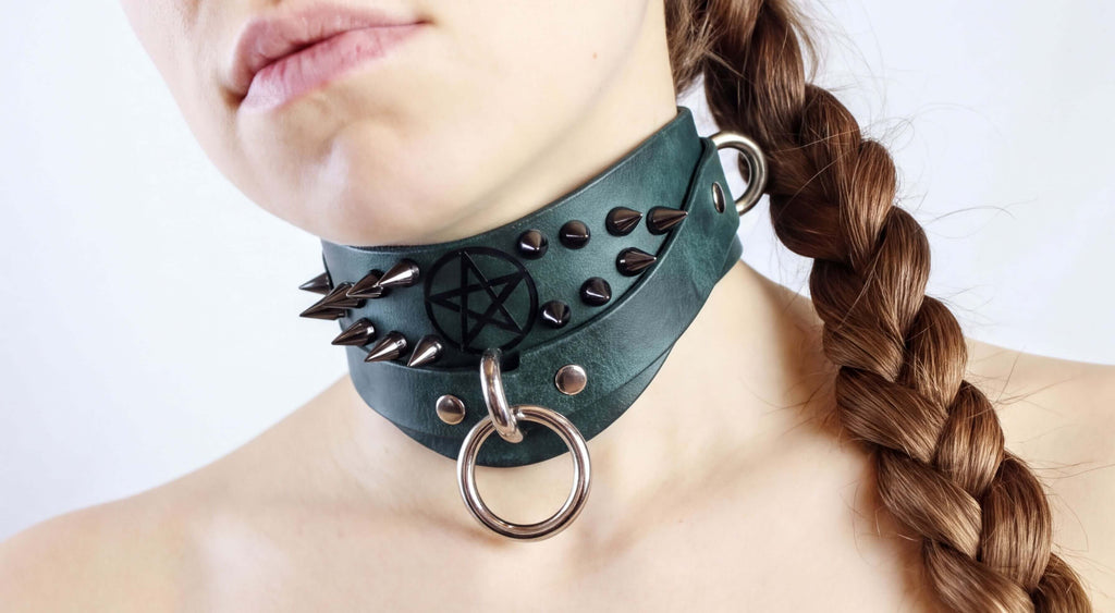 A close-up of a woman's neck with a green leather choker necklace adorned with spikes and a star-shaped emblem.