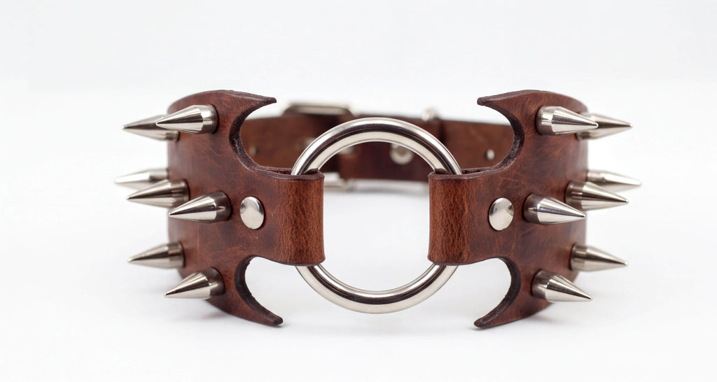A brown leather collar with spikes protruding from it, and a metal ring in the center.