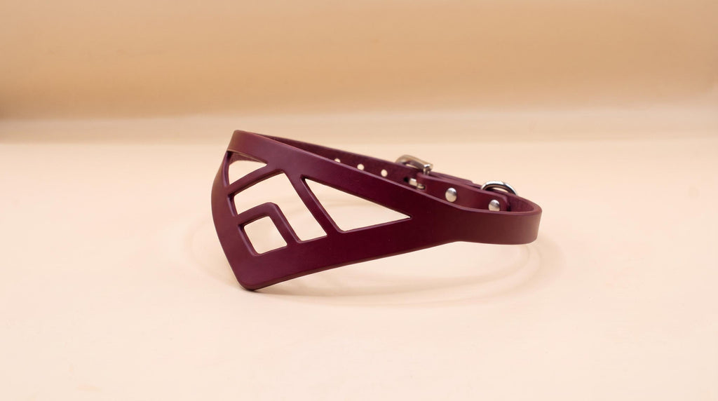 A burgundy-colored leather collar with a geometric cutout design.