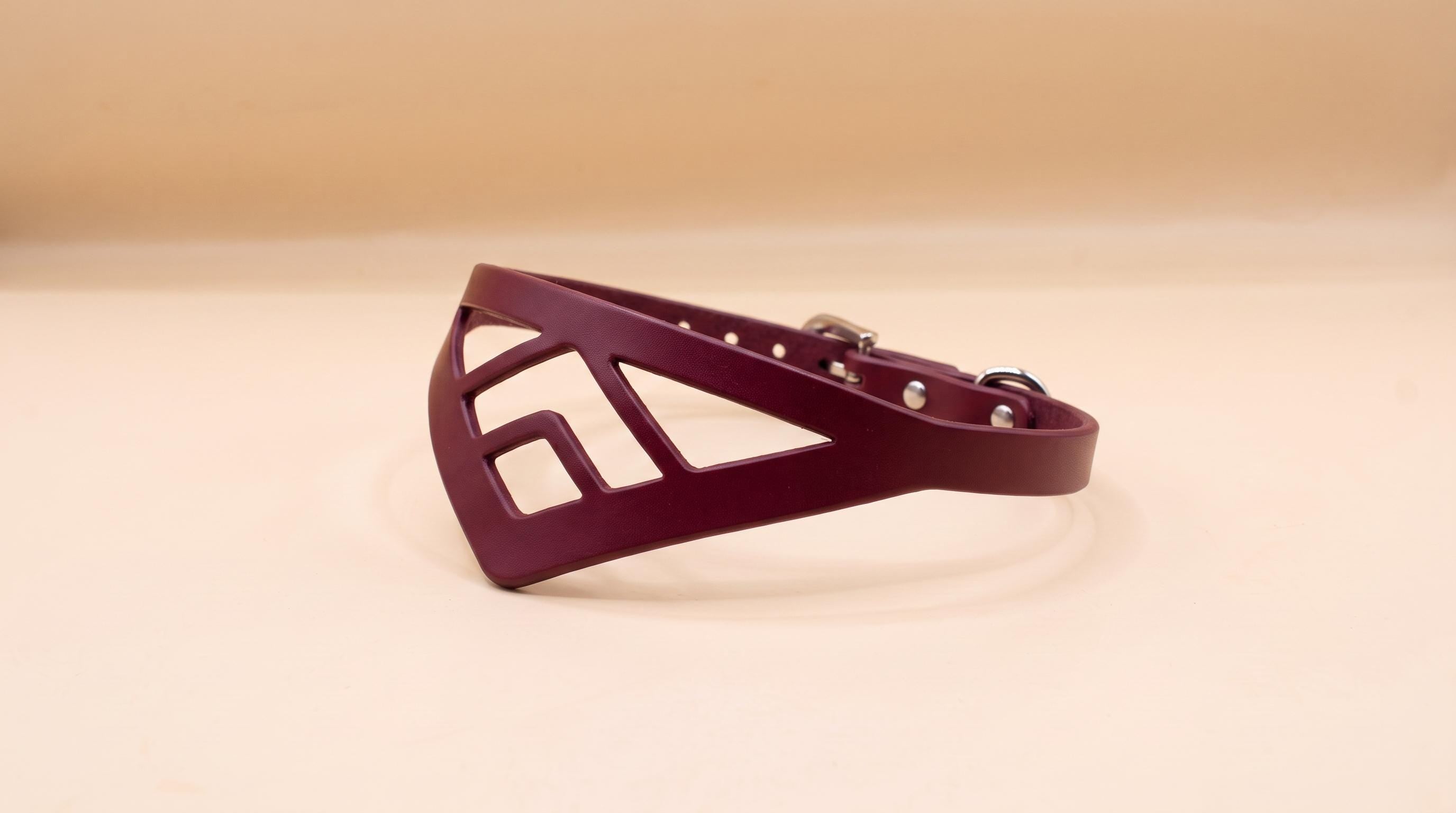 A burgundy-colored leather collar with a geometric cutout design.
