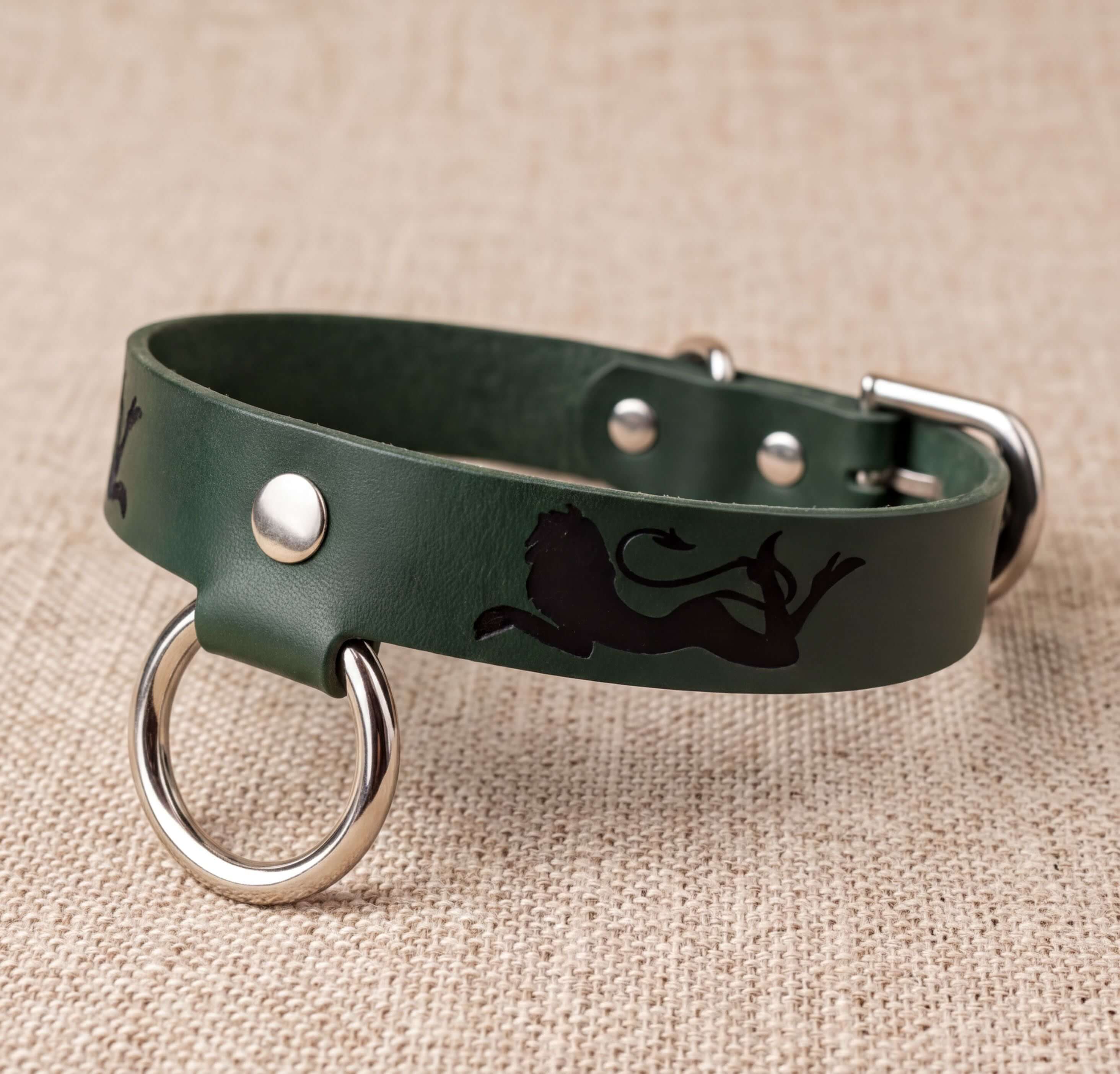 A green leather dog collar with a silver metal ring and a black lion silhouette design.