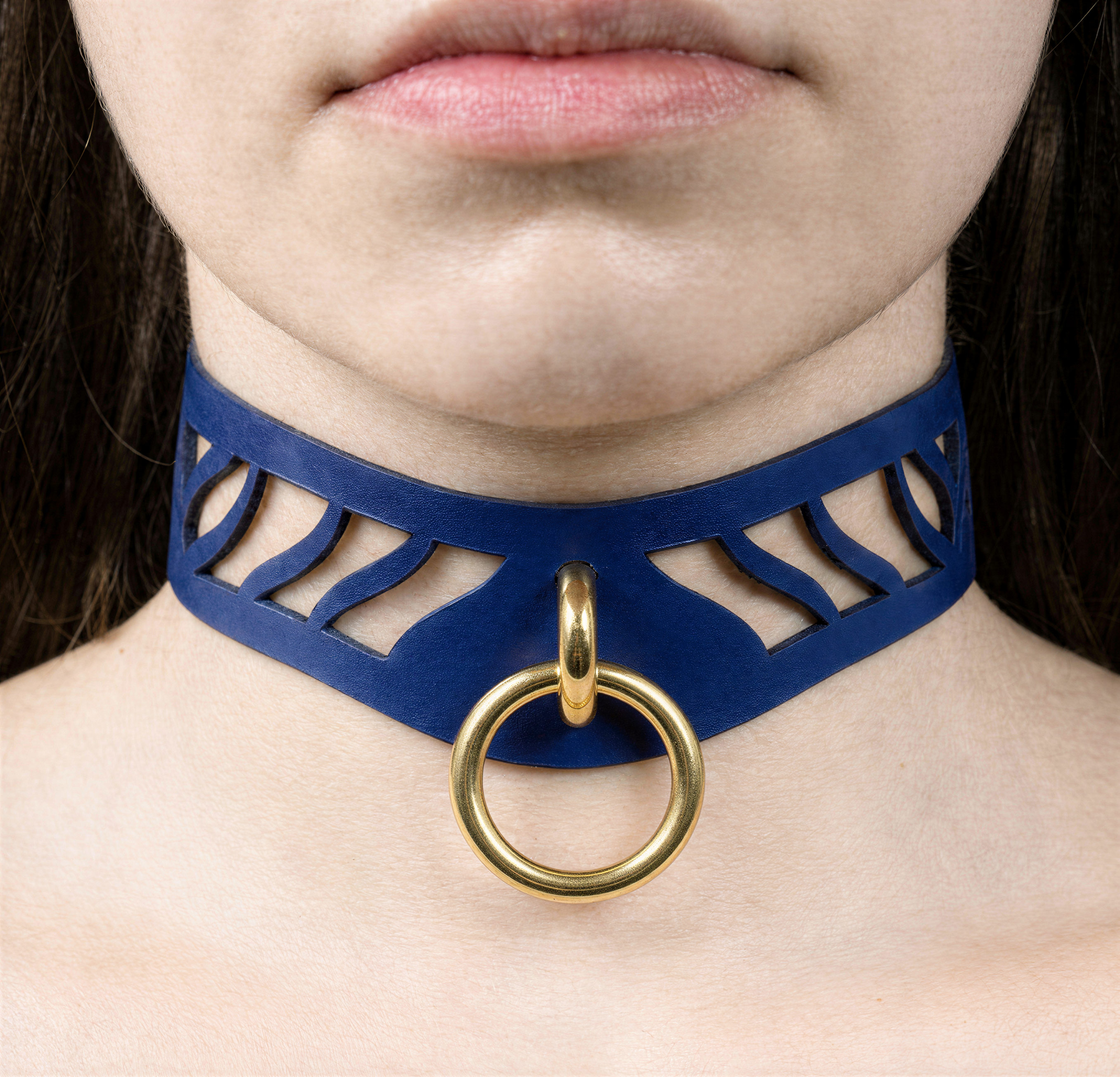 A close-up of a person's neck and chest area wearing a blue choker necklace with a gold ring.