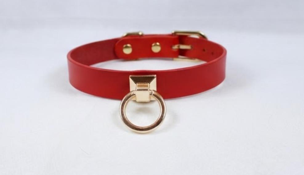 A red leather choker collar with a gold-colored metal ring and buckle.
