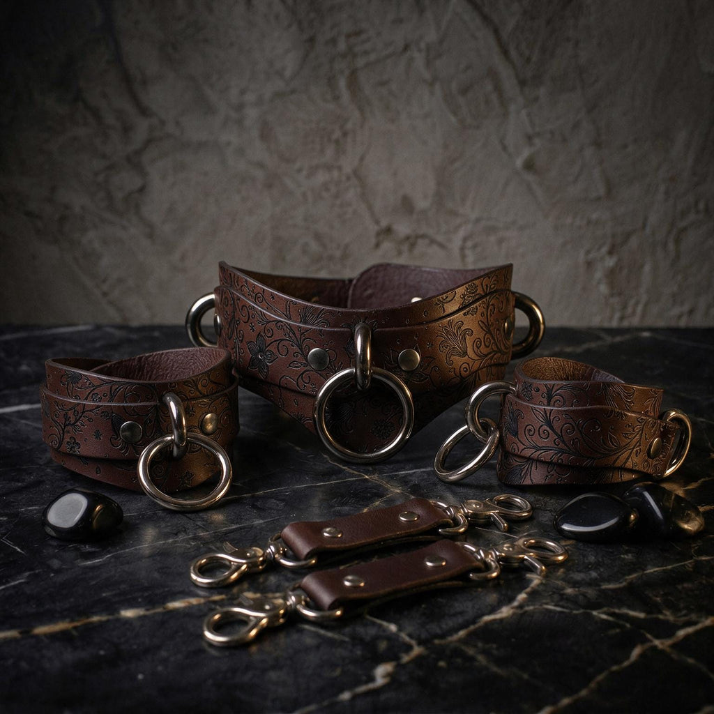 A set of brown leather straps with metal rings and buckles, arranged on a dark surface.