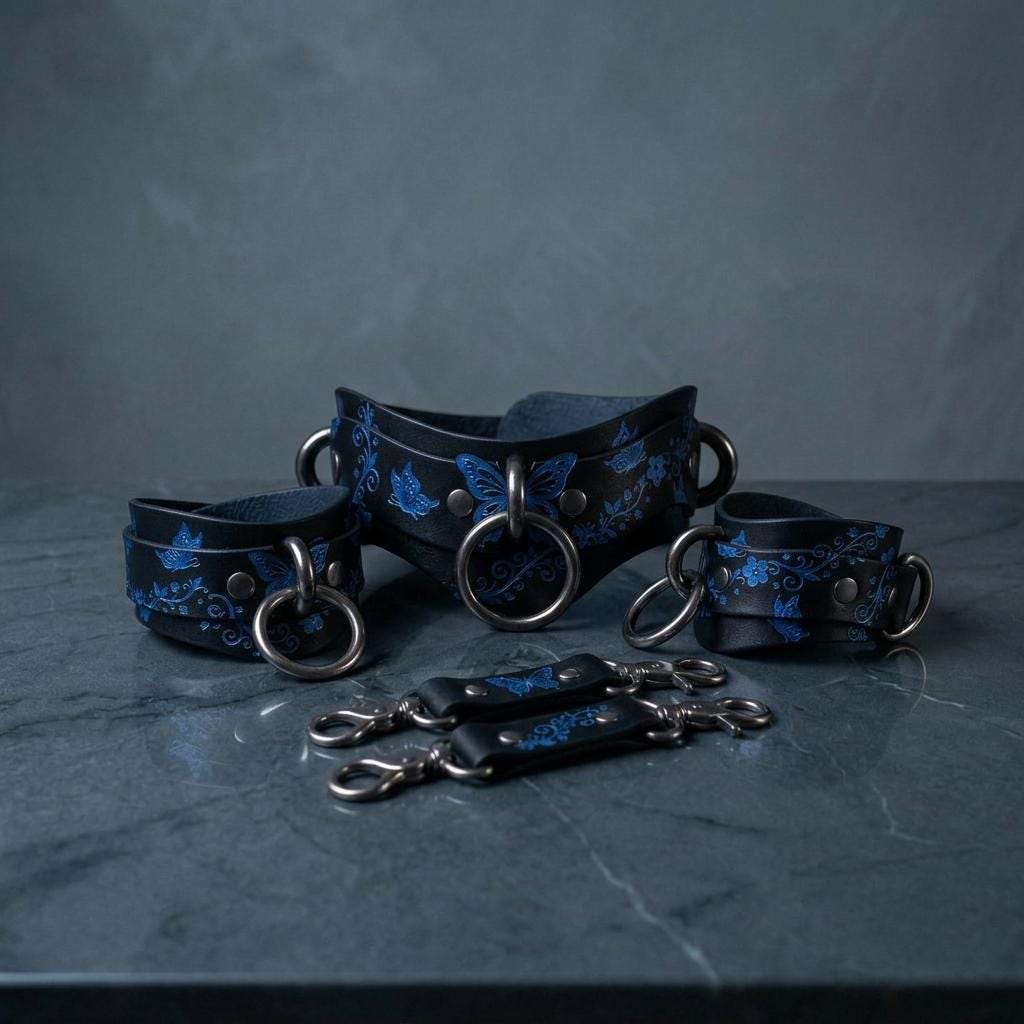 A set of black leather choker necklaces with blue floral designs, arranged on a gray surface.