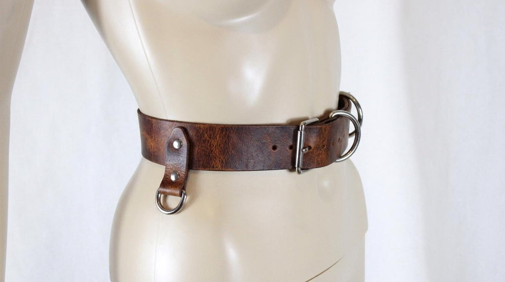 A mannequin wearing a brown leather belt with metal buckles.