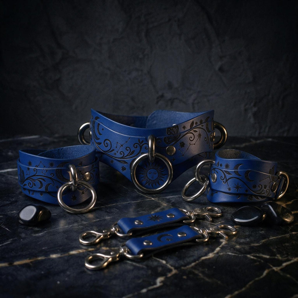 A collection of blue leather accessories, including choker necklaces and bracelets, with intricate designs and metal hardware, displayed on a dark surface.