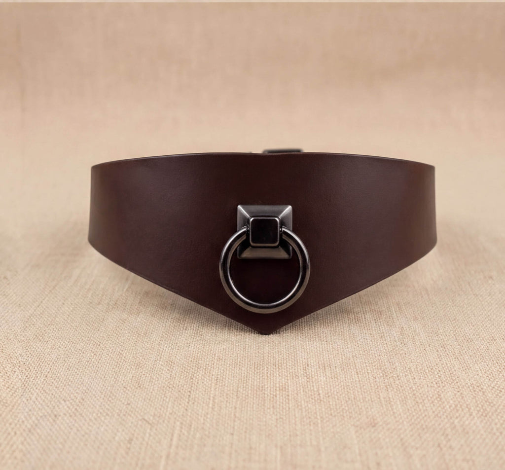 A brown leather choker necklace with a metal ring and a square-shaped metal piece on the front.