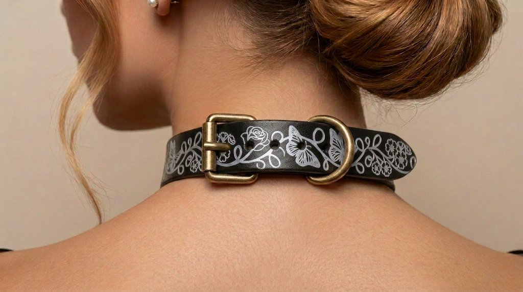 A close-up view of a woman's neck and shoulders, focusing on a decorative black leather choker necklace with a floral pattern and a gold-colored buckle.