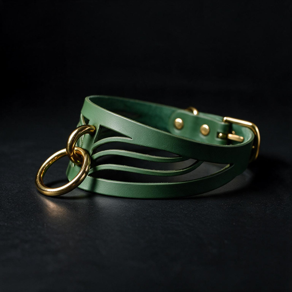 A green leather choker necklace with a gold-colored metal clasp and a unique, curved design.