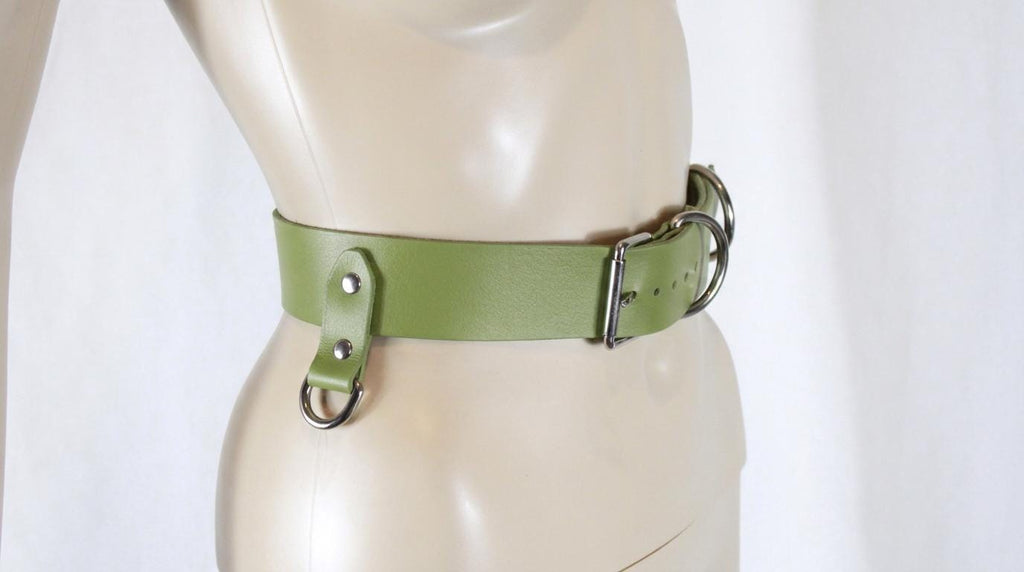 A mannequin wearing a green leather belt with metal buckles.