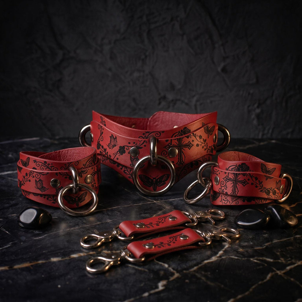 A set of red leather choker necklaces with metal rings and decorative patterns, displayed on a dark surface.
