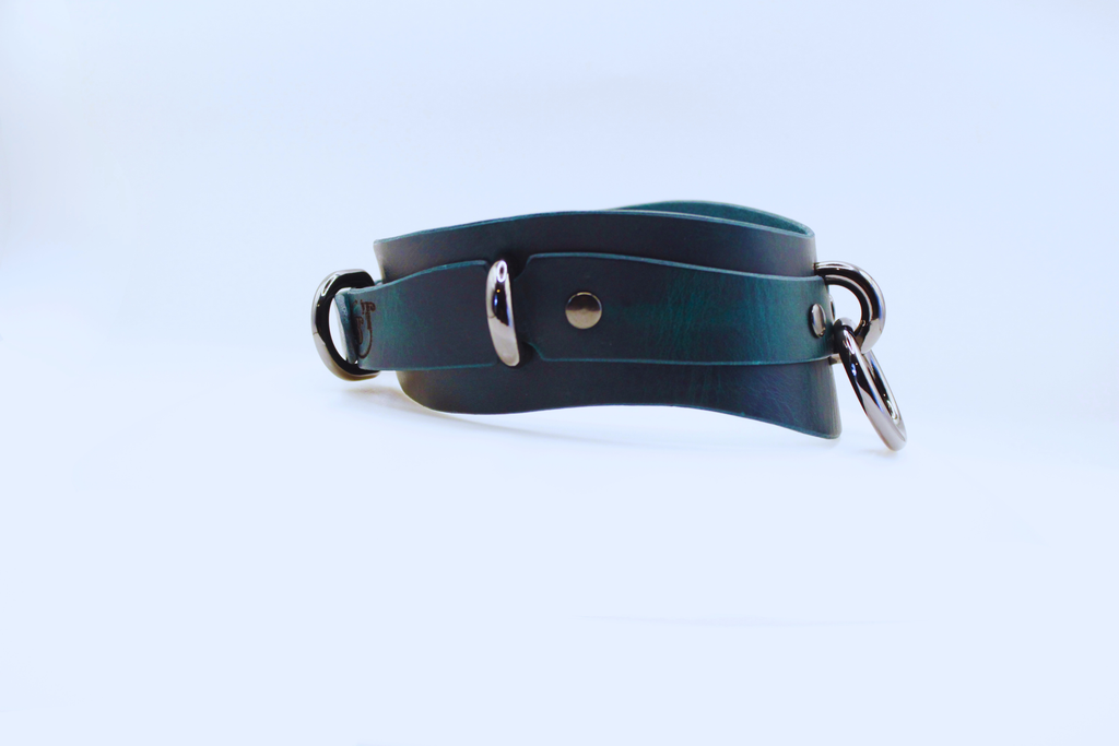 A dark green leather choker necklace with metal rings and a metal buckle.