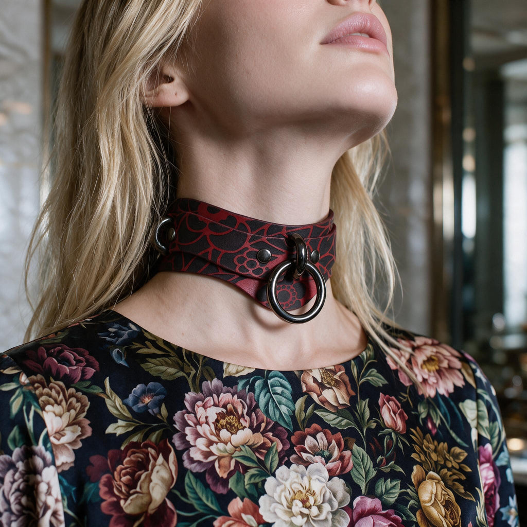 A woman wearing a red and black choker necklace with a floral pattern, posing with her eyes closed.