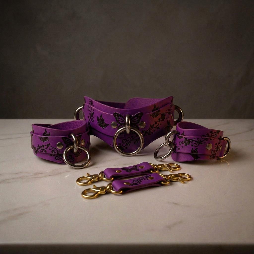 a set of purple leather straps with floral designs and metal rings, arranged on a white surface.