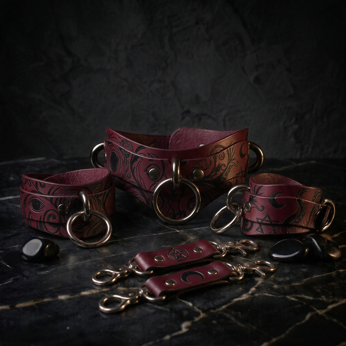 A collection of burgundy leather straps with metal rings and buckles, arranged on a dark surface.
