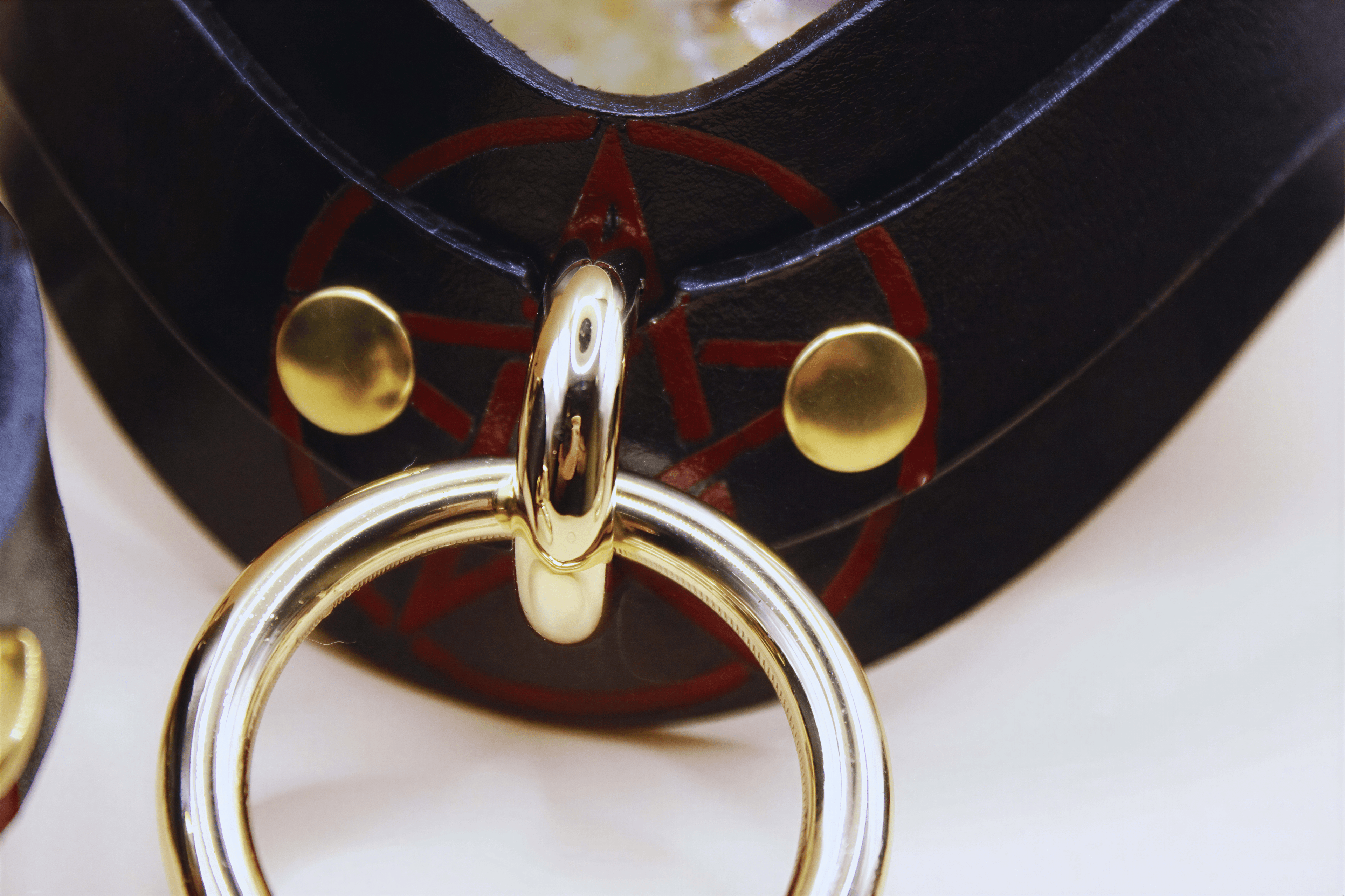 Close-up of a handcrafted pentagram BDSM collar featuring a gold ring and black leather, perfect for discreet day wear.