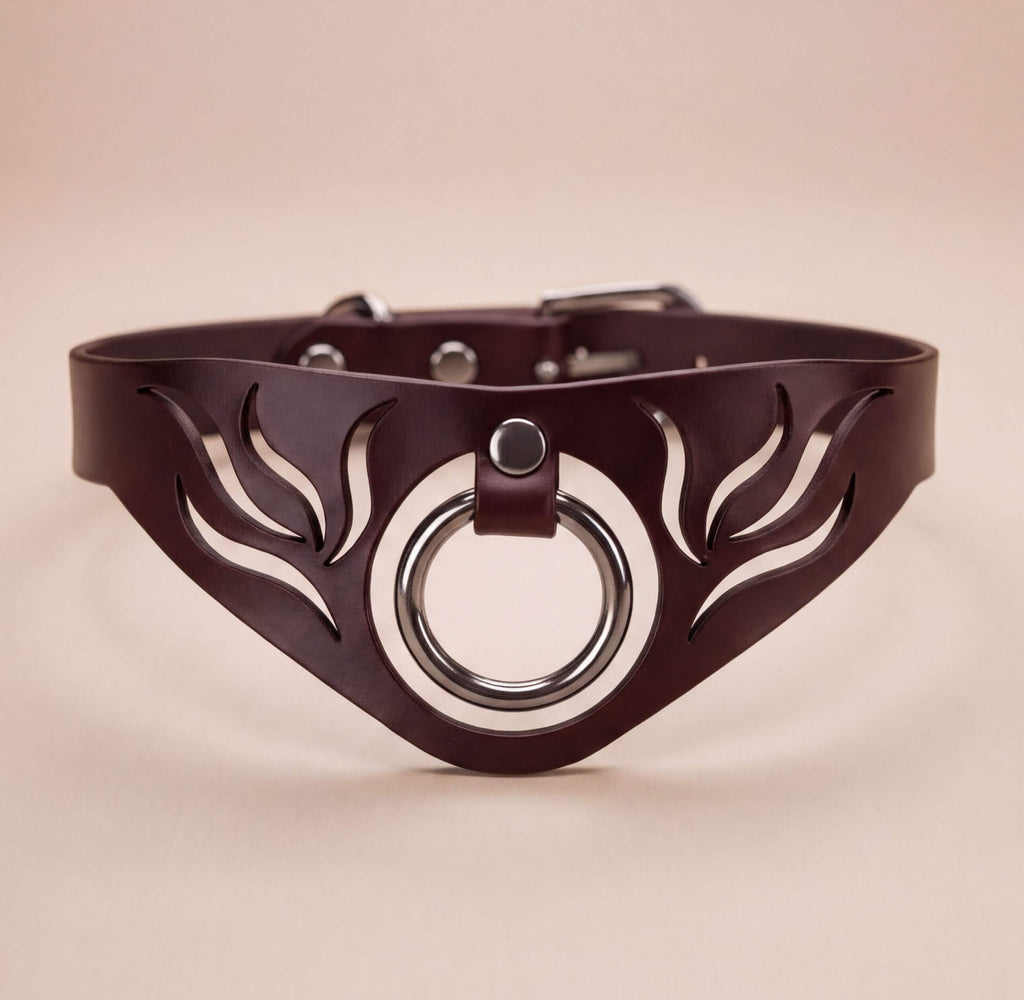 A brown leather choker necklace with a circular metal ring and leaf-like cutouts on the front.