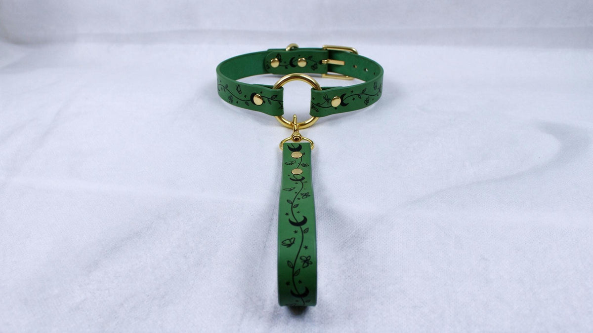 A green leather collar with a gold buckle and a matching green leash attached to it, resting on a white surface.