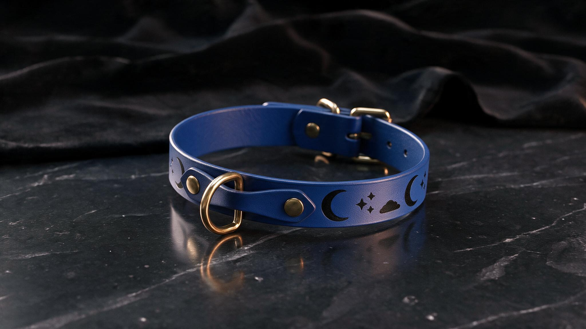 A blue leather collar with a moon and star design sits on a dark surface.