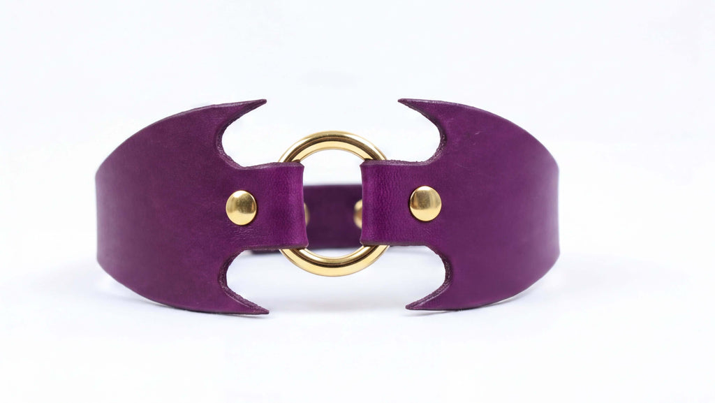 A purple leather choker necklace with a gold-colored metal clasp.