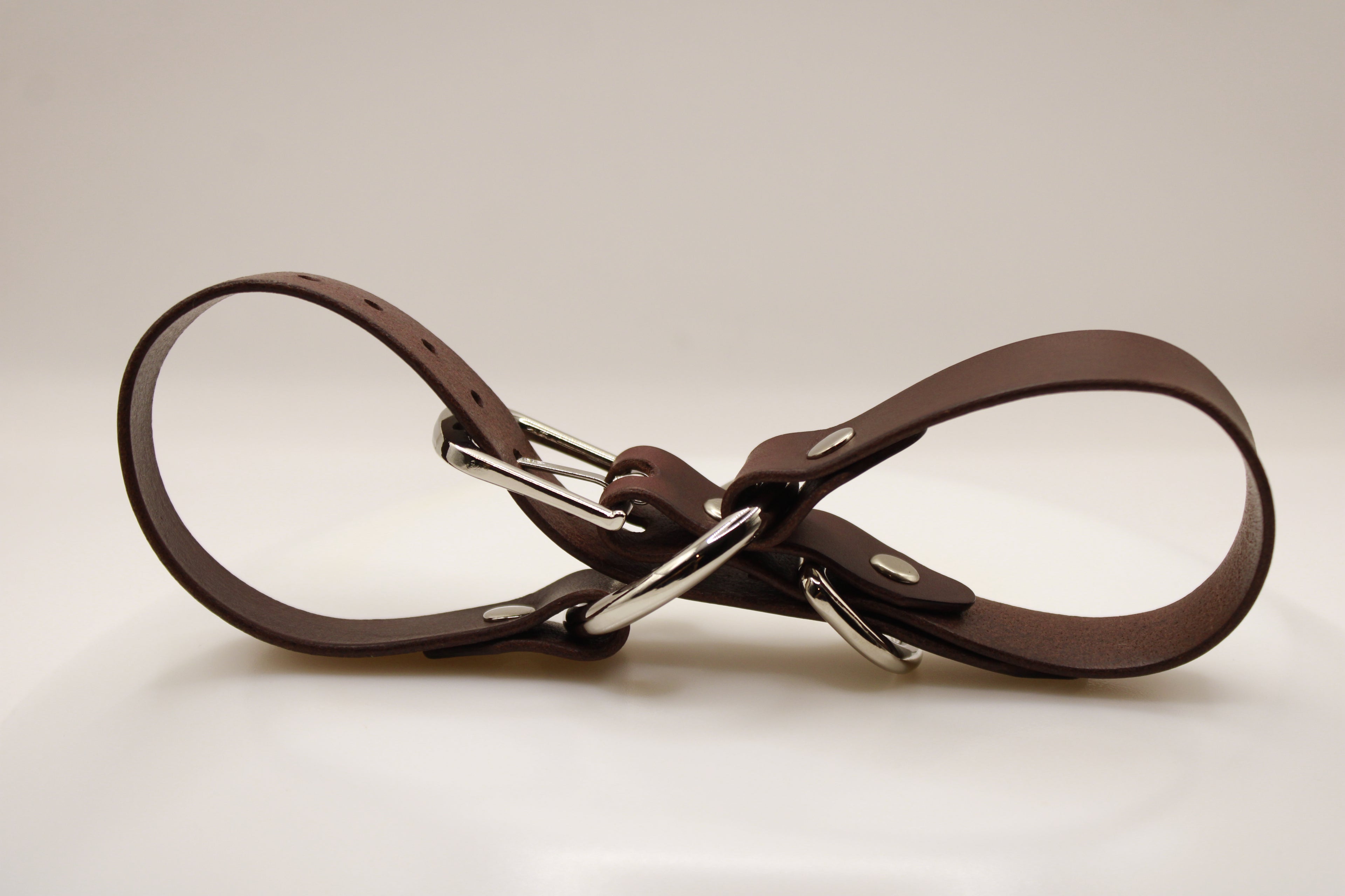 A brown leather belt with silver buckles is shown in the image.