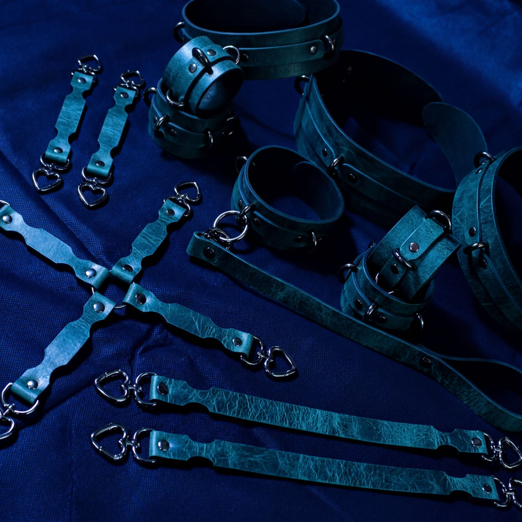 a collection of leather straps and restraints arranged on a dark blue background.