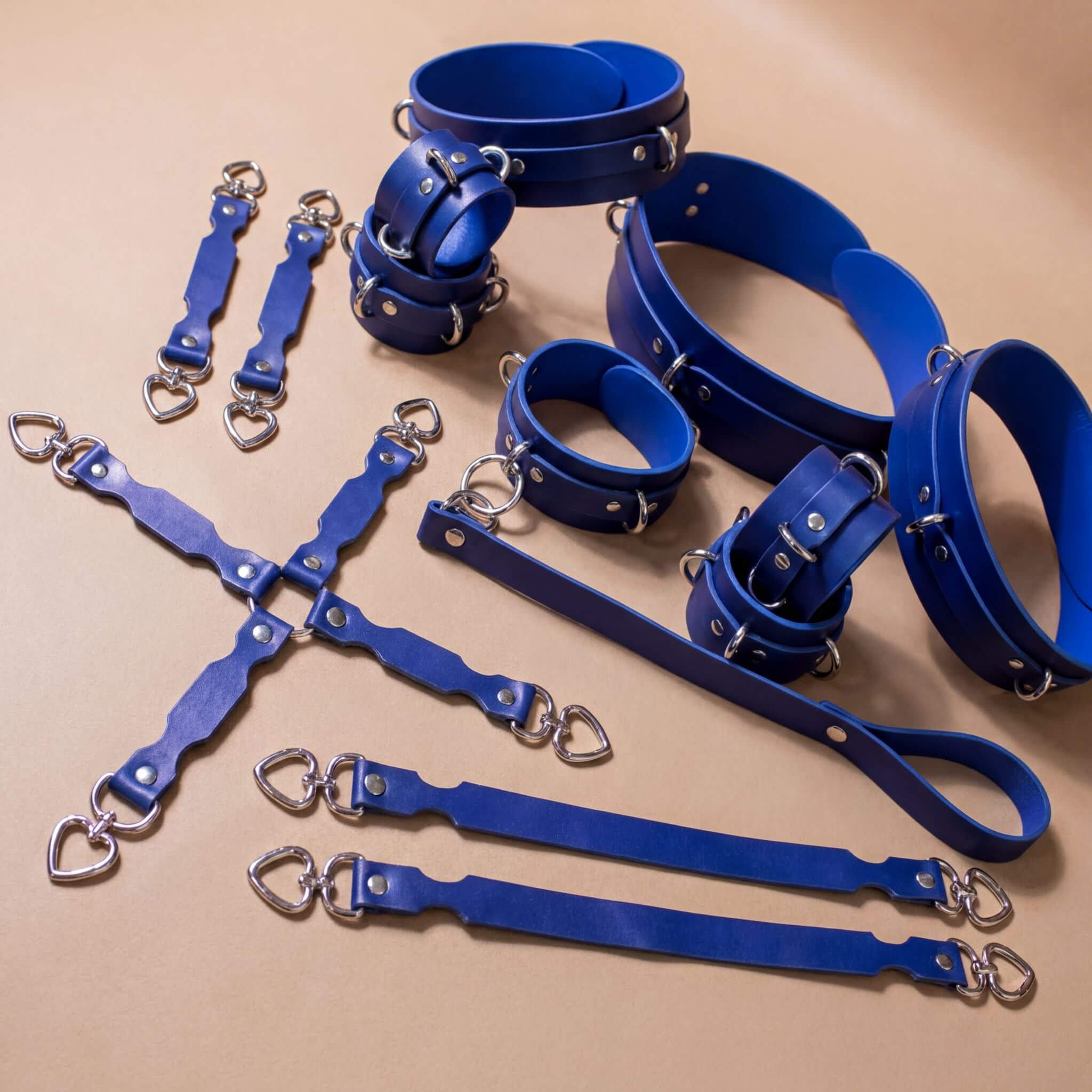 A collection of blue leather straps and buckles arranged on a beige background.