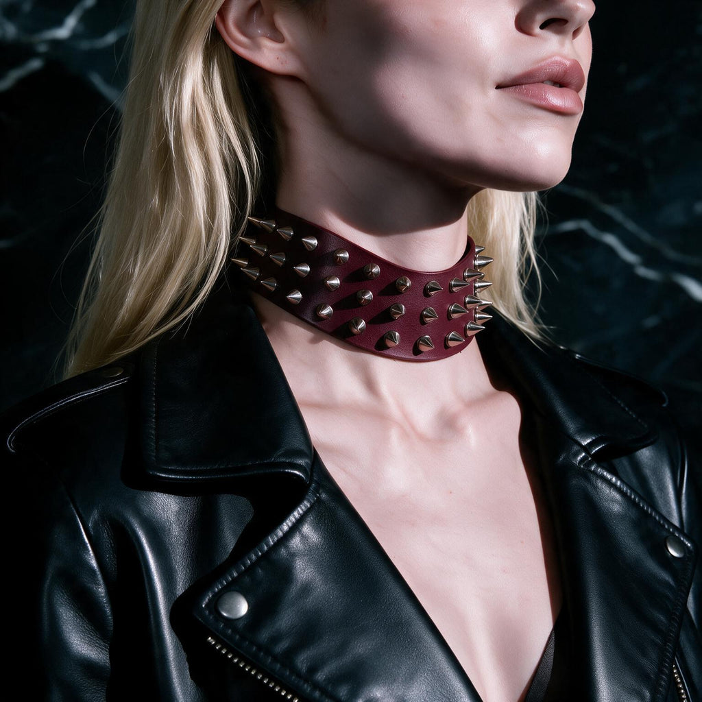 A close-up of a woman wearing a black leather jacket with a large, spiked choker necklace.