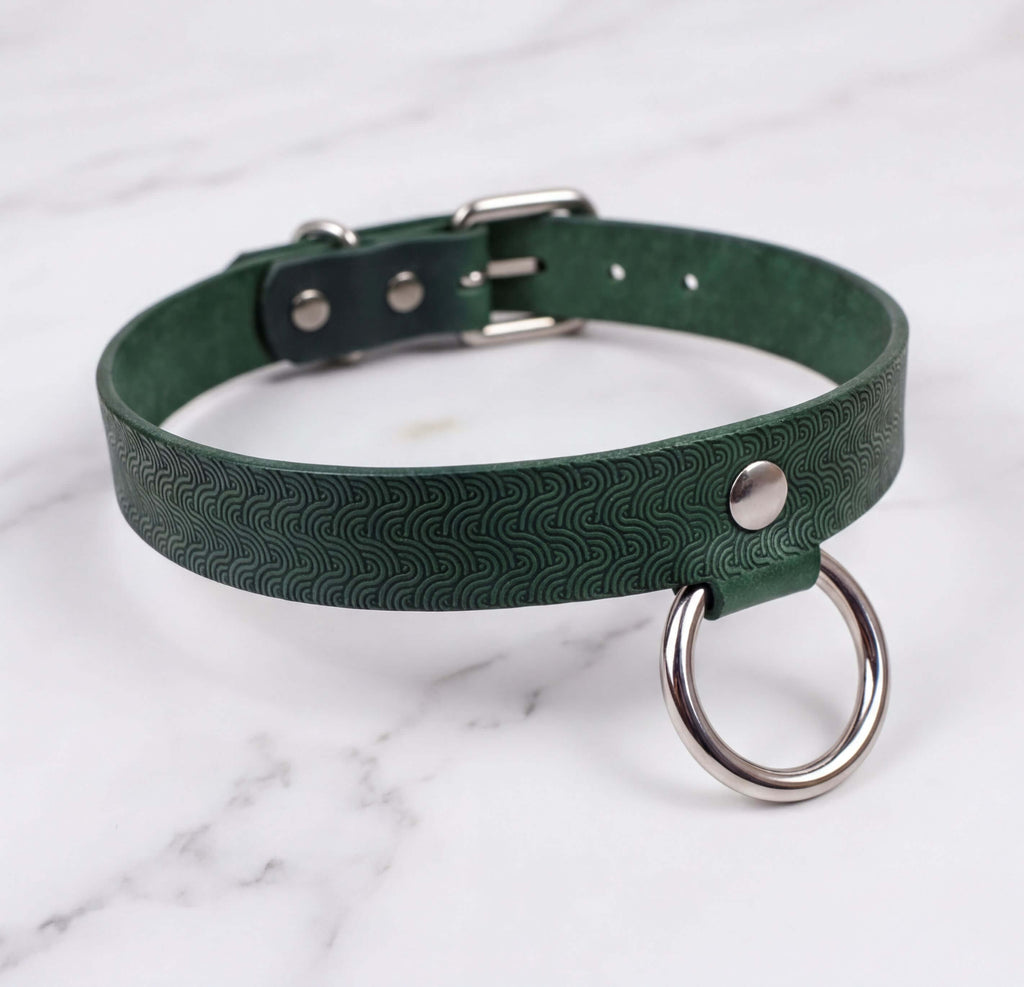 A green leather choker collar with a metal ring and buckle.