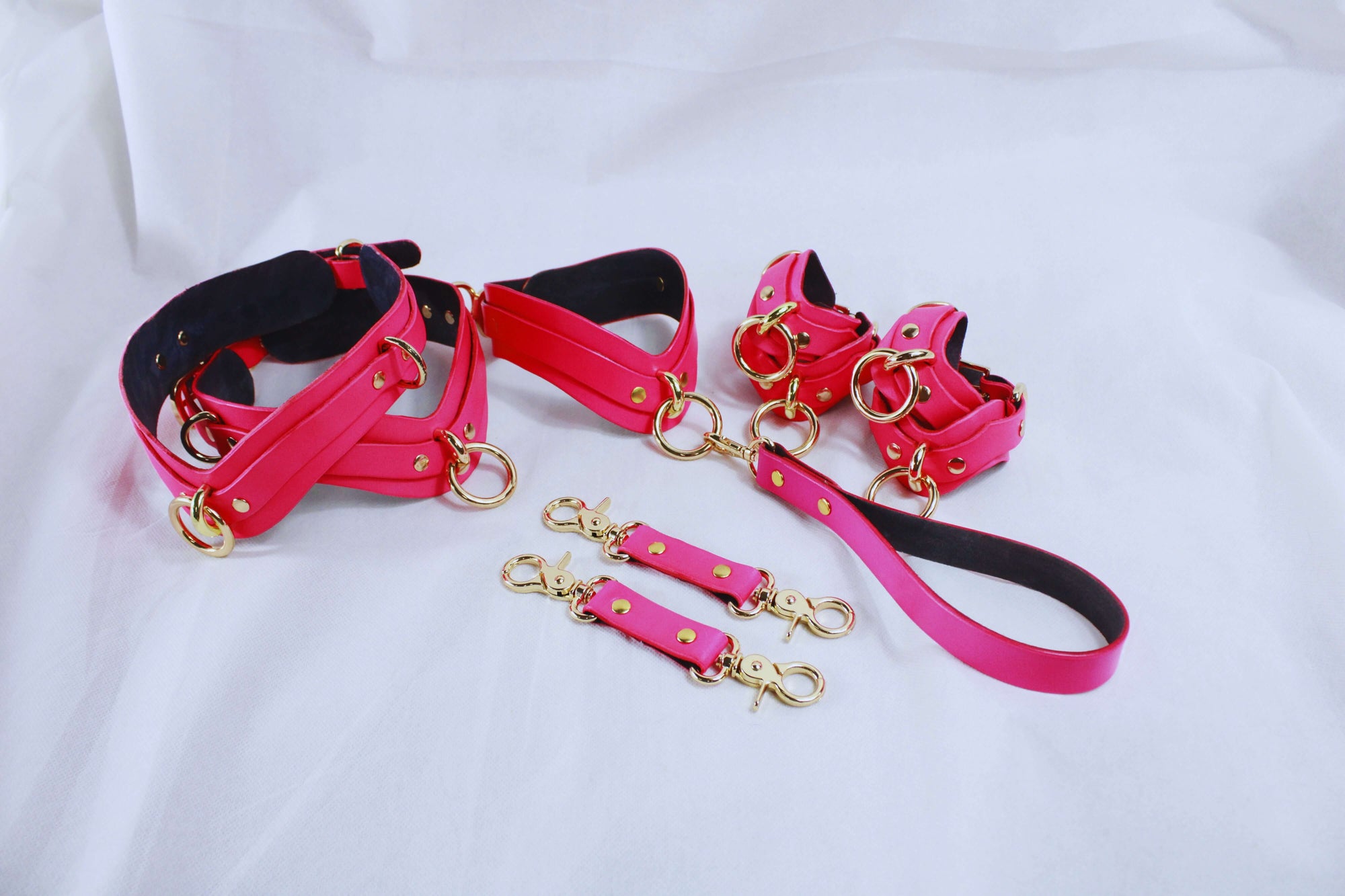 Elegant pink bondage restraint set including collar, cuffs, leash, and connectors for BDSM and submissive play.