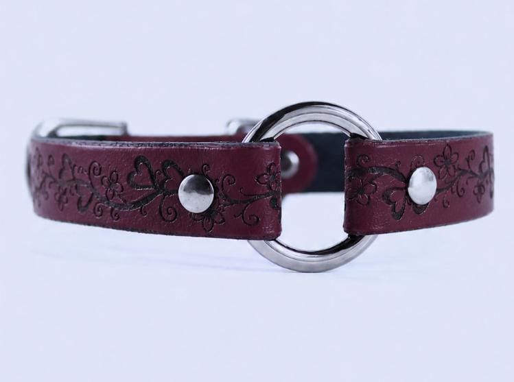 A burgundy leather collar with a circular metal buckle and floral designs.